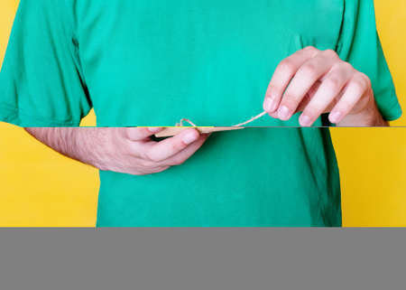 man in green shirt opening a gift on yellow background