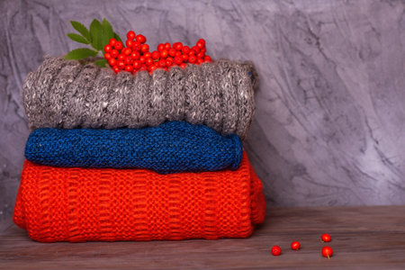 the pile of colorful wool scarves with rowan on the grey wooden background