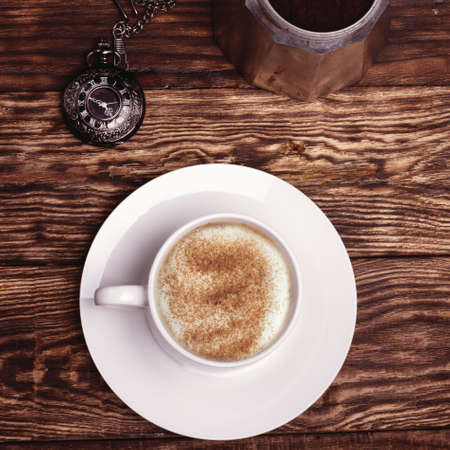 Cup of coffee, watch and coffeepot on a wooden backgroundの写真素材