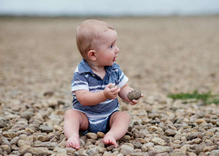 Small boy playng with stones on the seasideの写真素材