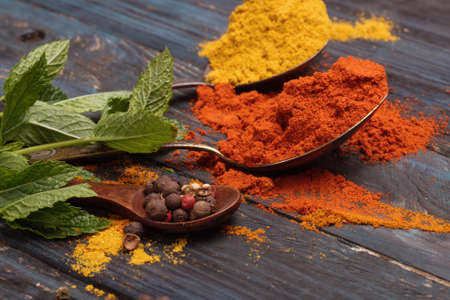 Colorful spices and wooden spoon on black backgroundの写真素材