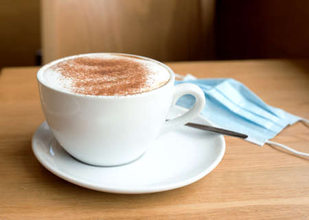 cup of coffee and face mask on the tableの写真素材