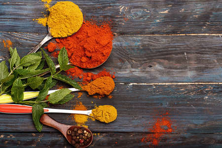 Colorful spices and wooden spoon on black backgroundの写真素材