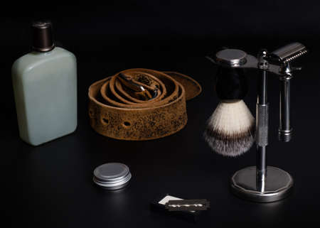 Razors, brush, balsam, perfume, and belt on a black background.の写真素材