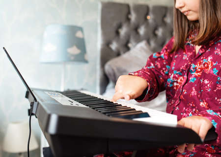 Girl in pajamas playing piano in a roomの写真素材