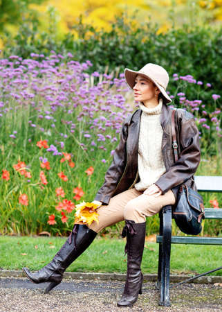 woman in hat sitting on the bench  in the autumn parkの写真素材