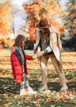 mother and daughter hugging and kissing together in autumn park