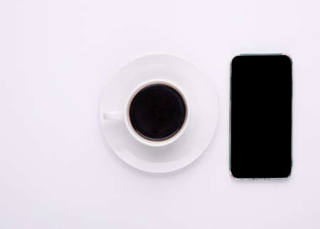 cup of coffee and phone on white backgroundの写真素材