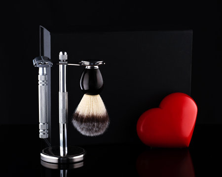 Razor and brush on stand and black box, red heart on a black ackgroundの写真素材
