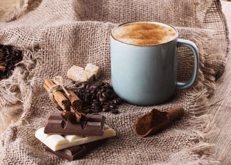 cup of coffee, chocolate, beans, anise and cinnamon on wooden backgroundの写真素材