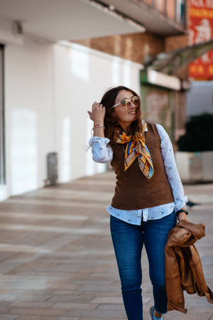Asian woman in a leather  coat and jeans walking around Europe cityの写真素材