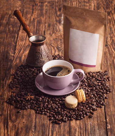 purple cup of coffee, macaroons,  beans, turkish coffee pot, and craft paper pouch bag on wooden backgrounの写真素材