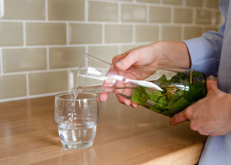 woman pouring fresh water into a glass from a decanterの写真素材