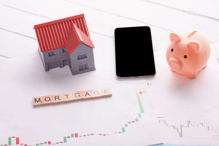 piggy bank, phone and house on mortgage chart and title mortgageの写真素材
