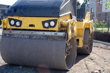 Drum Ride On Roller compacting freshly laid tarmac during roadworks and new footpath construction