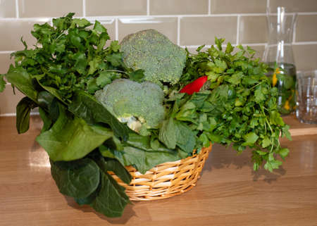 fresh vegetables in a basket on table in kitchenの写真素材