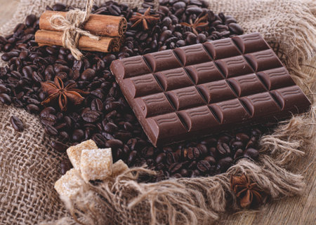 chocolate, coffee beans, anise and cinnamon on wooden background