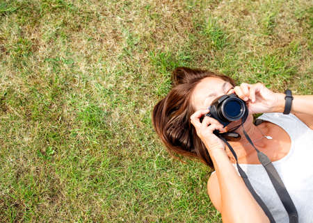 Asian woman holding camera on the dry grass in the gardenの写真素材