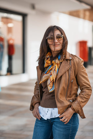 An Asian woman in a leather coat and jeans walking around Europe cityの写真素材