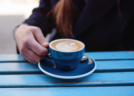 woman holding cup of coffee in the cafe on the table