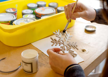 a person decorating handmade wooden Christmas decorations in traditional woodworking shopの写真素材