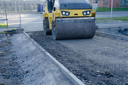 Drum Ride On Roller compacting freshly laid tarmac during roadworks and new footpath constructionの写真素材
