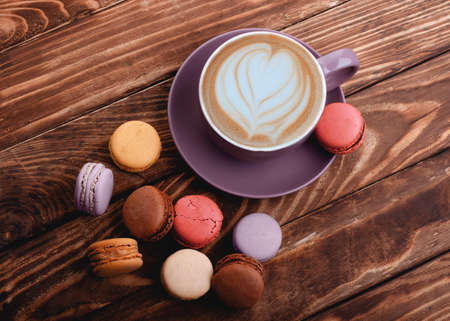 purple cup of coffee with heart  and colorful macaroons on the wooden backgroundの写真素材