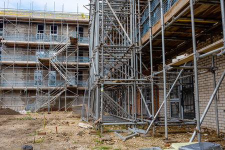 Scaffold and temporary access stairs erected on new housing development construction site around new multi-storey house to allow cladding, windows and roof installationの写真素材