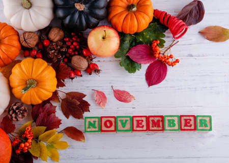 autumn leaves and pumpkins with text November on wooden backgroundの写真素材