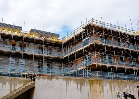 Scaffolds erected around new multistorey brick house on new residential housing development site to allow safe acces to place of work and windows and roof installationの写真素材