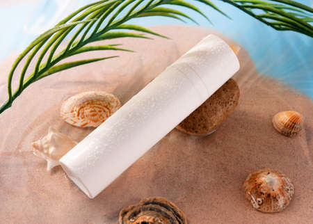 a white tube for cream, shaving foam, spray, shampoo with drops lying among shells on the sand on the seasideの写真素材