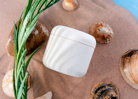 a white jar of cream lies on the sand on the seaの写真素材