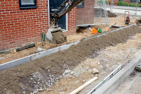 Construction workers finishing construction of new residential house and installing footpath in front of it.の写真素材