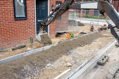 Construction workers finishing construction of new residential house and installing footpath in front of it.の写真素材
