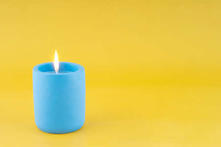 Blue candle on yellow background Space for textの写真素材