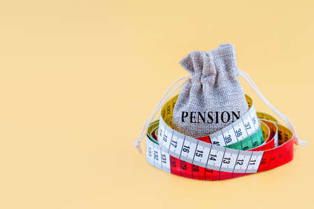 a small canvas bag with word PENSION wrapping with a centimetre on a yellow backgroundの写真素材