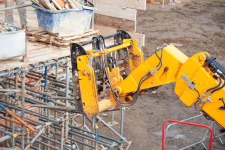 Telehandler on construction site lifting heavy steel box full of scaffolding partsの写真素材