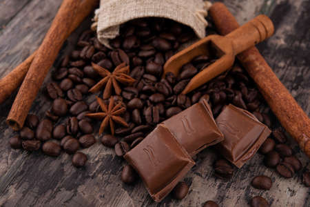 chocolate, cinnamon sticks  and coffee beans on wooden backgroundの写真素材