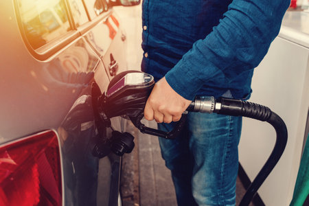 A man at the gas station filling the tank of his car with diesel to the top level before a long journey as fuel prices is going upの写真素材