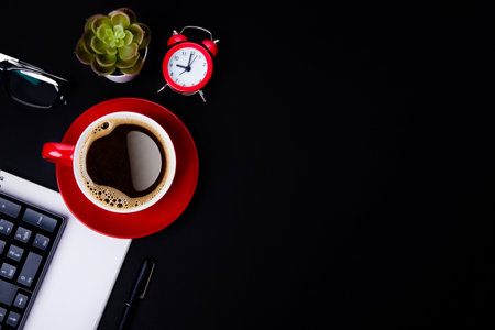 red cup of coffee, pen, glasses, alarm,  plant, phone, and paper on a black background  as workplace top view space for textの写真素材