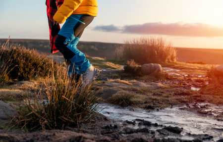 Woman in yellow coat and orange scarf walking and reaching the destination on top of hill or mountain at sunrise. British cold winter. Local tourism conceptの写真素材