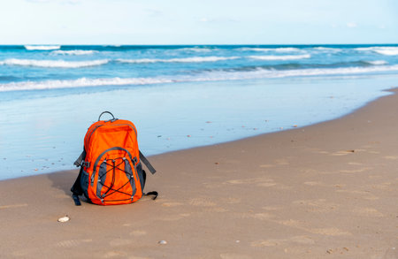 Orange rucksack on the seaside against the sea in fantastic weather. Travel insurance concept. Travel lightの写真素材