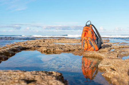 Orange backpack on the seaside against the sea in fantastic weather. Travel insurance concept. Travel lightの写真素材