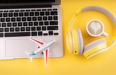 Travel flatlay. Laptop, coffee, headphones and plane on green  background. Planning summer vacation concept. Take music or book on a journey. Summer workspace.の写真素材