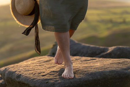 Woman in green dress reaching the destination, sitting and resting  on top of mountain in the Peak District  at sunrise.   Local tourism concept.の写真素材