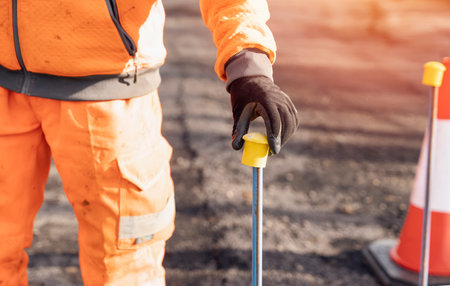 Builder placing yellow plastic safety protecting caps on top of road setting out steel pins on a road improvement projectの写真素材