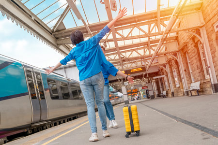 Beautiful couple at railway station waiting for the train. Woman and man running to board a trainの写真素材