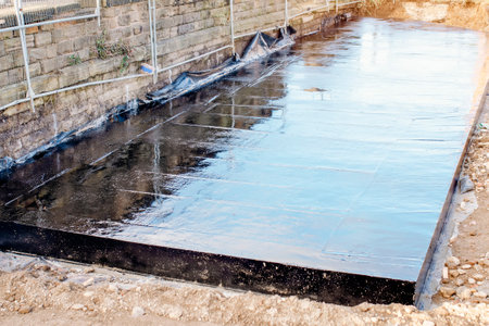 waterproof coating. Builder applying waterproofing bitumen mastic on concreteの写真素材