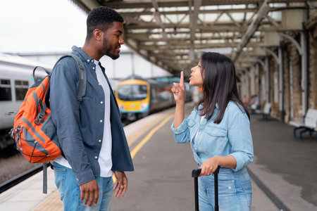 a young couple swearing and arguing with each othe at the train station on the platform The concept of disagreements in the familyの写真素材