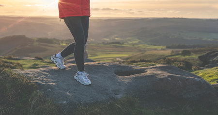 A woman walking on a rocks on the mountain trail at cold autumn evening. Hiking and active lifestyle concept toned imageの写真素材
